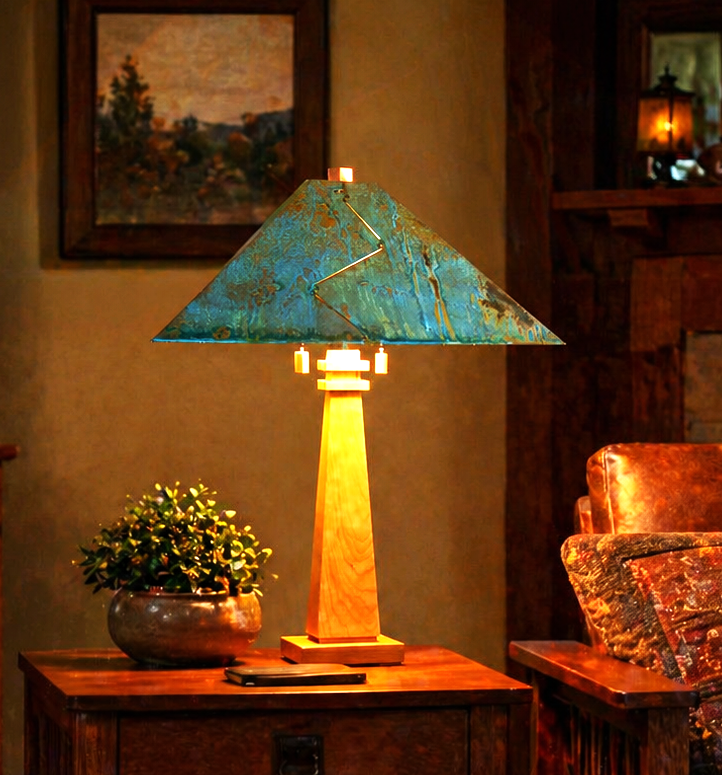 A rustic table lamp with a triangular teal-blue distressed metal shade and a warm yellow illuminated wooden base, styled on a wooden side table in a cozy living room setting.