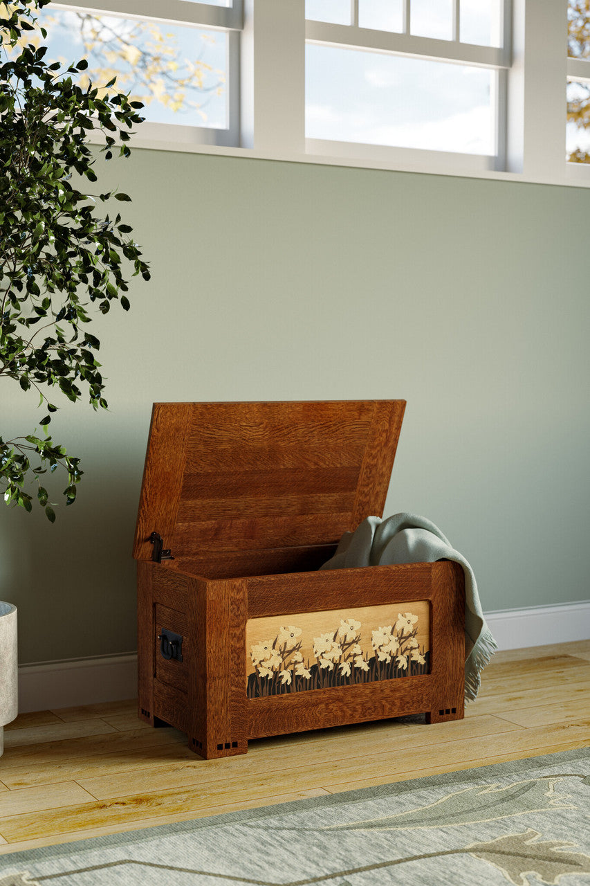 Wooden storage chest with floral design on a wooden floor near a window.