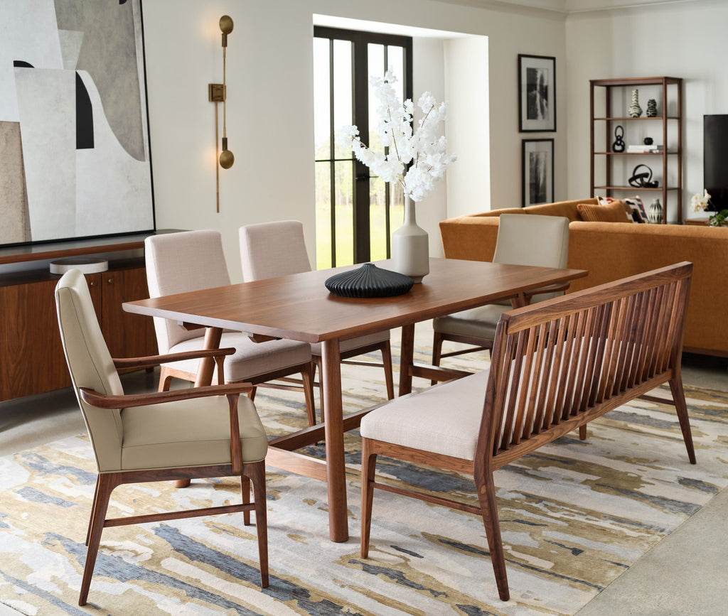 Dining room with wooden table and chairs, rug, and wall art.