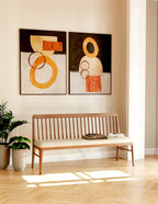 Wooden bench with abstract wall art in a room with light wood flooring and a plant.
