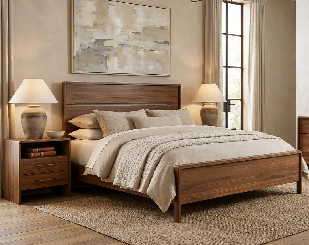 A medium brown wooden bed frame with a matching headboard and footboard, styled in a warm, neutral-toned bedroom with beige bedding, two matching nightstands, table lamps, and a textured rug.