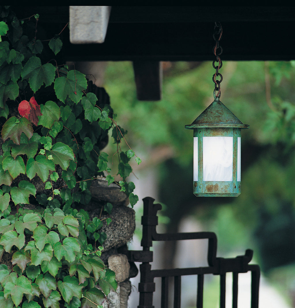 Vintage-style hanging lantern with green patina on a blurred natural background