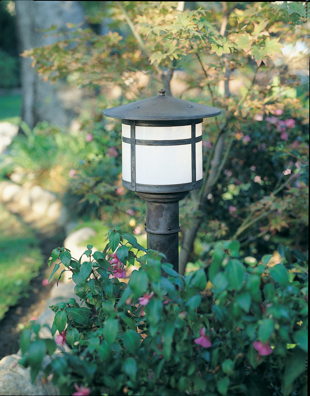 Garden light fixture in a natural setting with plants and flowers.