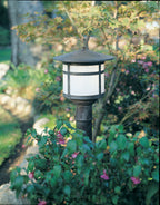 Garden light fixture in a natural setting with plants and flowers.