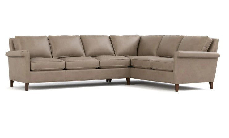A light taupe sectional sofa with a right-facing L-shape, featuring plush seat and back cushions and dark brown wooden legs, shown against a plain white background.