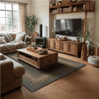 A styled living room featuring a large woven area rug in blue-gray and beige tones, a wooden coffee table with casters, a beige sofa, a wood TV stand, and a rustic wooden wall shelf.