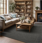 A large charcoal gray textured area rug in a cozy, modern living room setting with a beige sofa, wooden coffee table, and a tall wooden bookshelf.