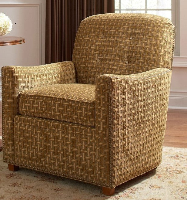 Patterned armchair in a room with curtains and a table.