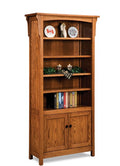 A tall wooden bookcase with a warm medium-brown finish, featuring five open shelves, decorative items on the top shelf, a green garland and candle holder on the middle shelves, and two cabinet doors at the bottom. The bookcase is shown against a plain white background.