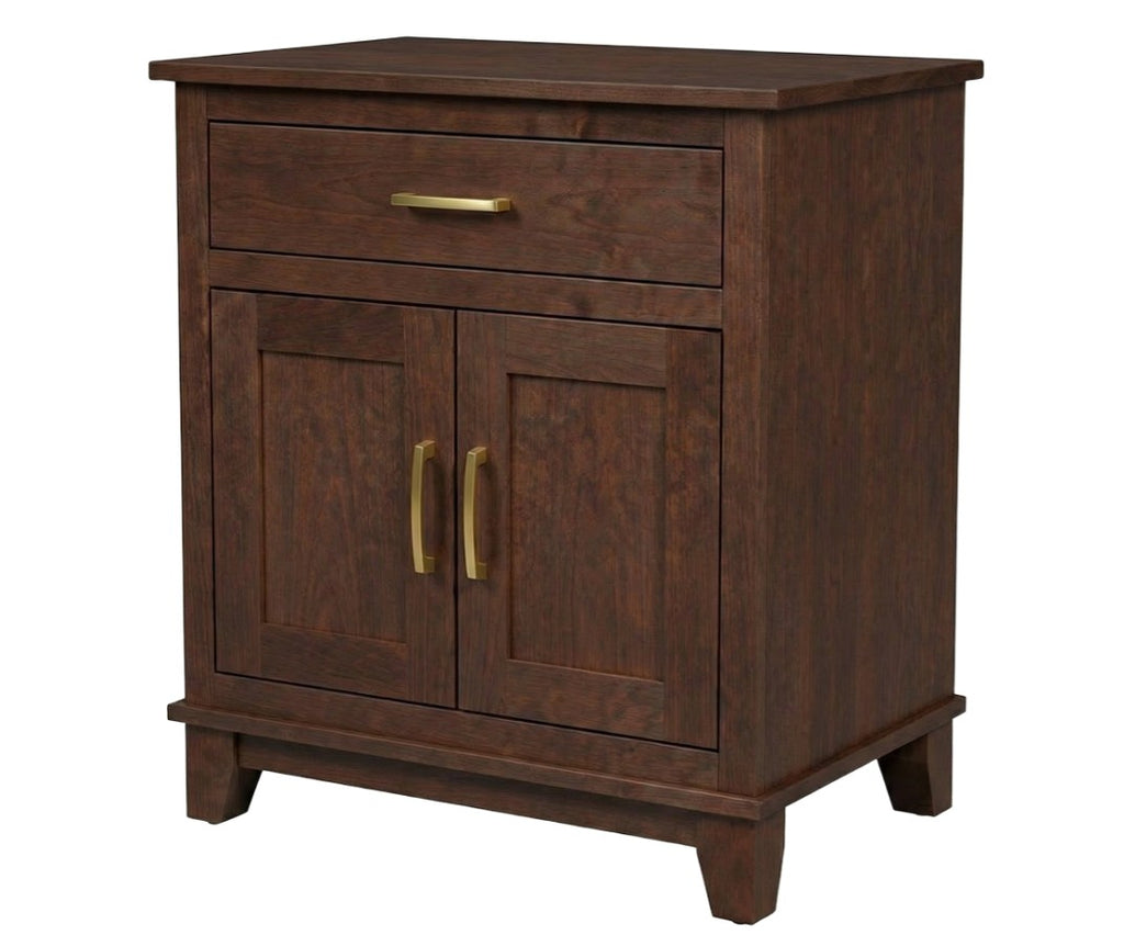A dark brown wooden cabinet with a single drawer on top and two paneled doors below, featuring brass-finished handles and legs, shown against a plain white background.