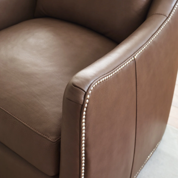 Close-up of a brown leather armchair with visible stitching details.