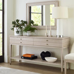 Light wood console table with decorative items in a room with a mirror and lamp.