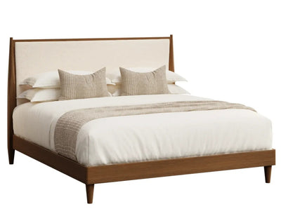 A modern medium brown wooden bed frame with a cream upholstered headboard, styled with white bedding, two textured beige pillows, and a beige throw blanket, shown against a solid white background.