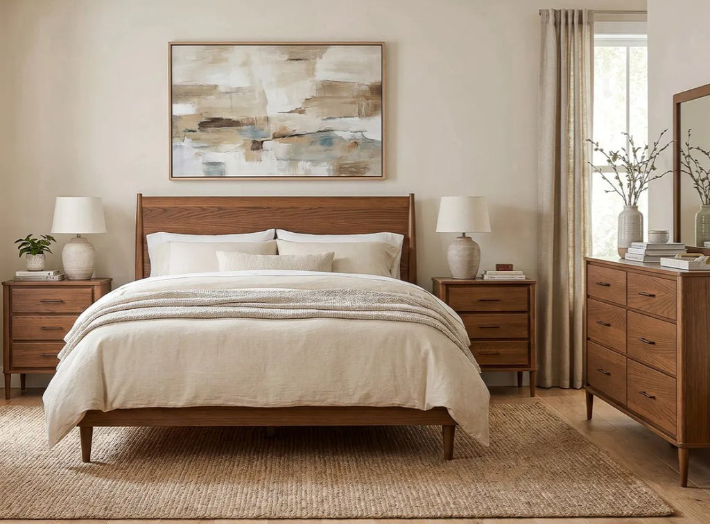 A styled bedroom featuring a wooden bed frame with cream bedding, matching wooden nightstands, a wooden dresser, and a large abstract painting on the beige wall.