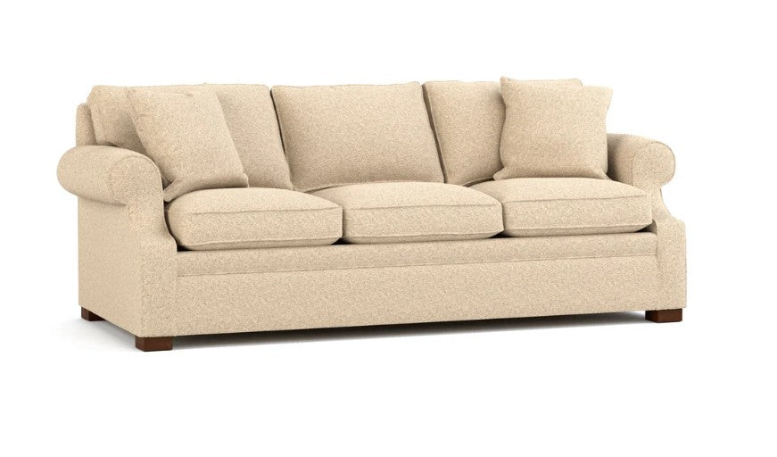 A three-seater upholstered sofa in a textured beige fabric, featuring four matching back cushions, rolled arms, and dark wooden legs, shown against a plain white background.