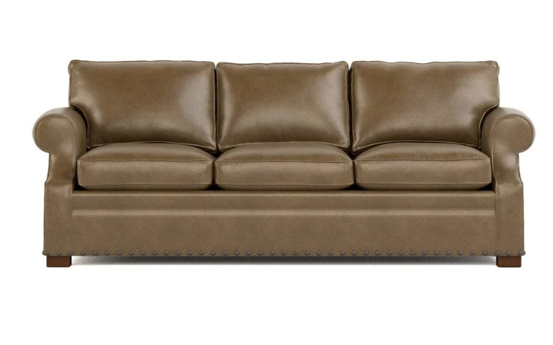 A three-seat leather sofa in a warm taupe-brown color, featuring rolled arms, three back cushions, three seat cushions, and nailhead trim along the front apron, shown against a plain white background.