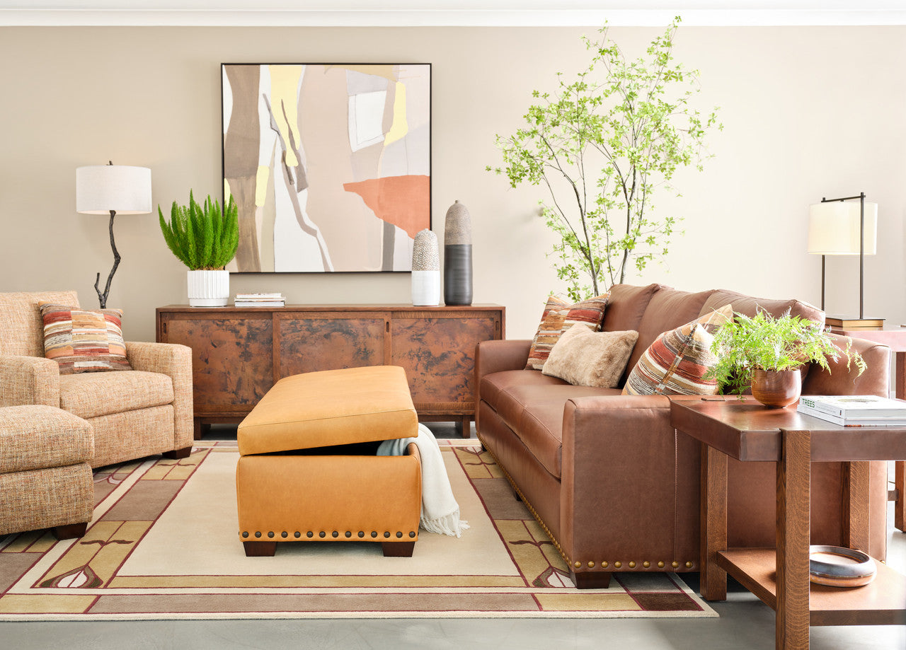 Living room with brown sofa, armchair, ottoman, and decorative elements.