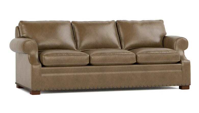 A three-seater leather sofa in a warm taupe-brown color, featuring rolled arms, deep seat cushions, and nailhead trim along the front, shown against a plain white background.