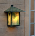 Decorative outdoor wall light fixture with artistic design on a wooden wall.