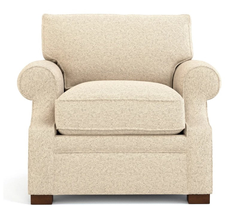 A classic upholstered armchair in a textured beige fabric, featuring rolled arms, a thick seat cushion, and dark brown wooden legs, shown against a plain white background.
