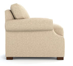 Side view of a modern armchair upholstered in a textured beige fabric, featuring a high back, wide armrests, and dark brown wooden feet, set against a plain white background.