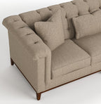 A close-up of a tufted loveseat sofa upholstered in a textured beige fabric, featuring dark brown wooden legs, shown against a light gray background.
