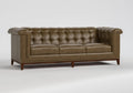 A classic Chesterfield-style leather sofa in a warm taupe-brown color, featuring deep button tufting, rolled arms, and dark wood legs, shown against a neutral light gray background.