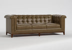 A classic Chesterfield-style leather sofa in a warm taupe-brown color, featuring deep button tufting, rolled arms, and dark wood legs, shown against a neutral light gray background.