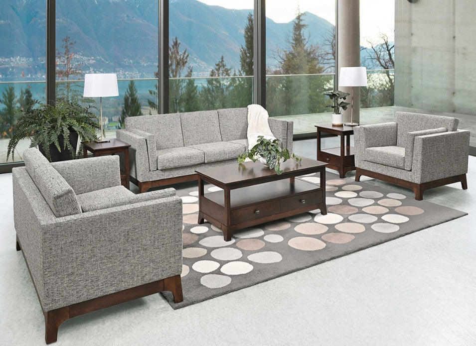 A 4-piece modern living room furniture set featuring a gray fabric sofa, two matching armchairs, and a dark wood coffee table, arranged on a patterned circular rug in front of a large window with a mountain view.