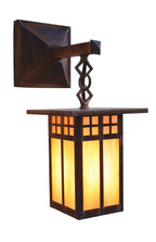 A dark brown wooden outdoor wall sconce with a warm yellow-orange glowing light, featuring a square backplate, decorative twisted metal support, and a rectangular lantern shade with geometric window panels.