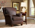 Brown leather armchair in a living room setting with a lamp and decor items.