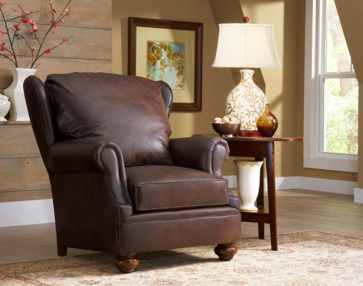 Brown leather armchair in a living room setting with a lamp and decor items.