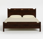 A dark brown wooden bed frame with a high headboard and footboard, styled with cream-colored bedding and two pillows against a light gray background.