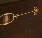 Close-up of a dark brown wooden surface with a decorative light wood inlay featuring a heart, oval, and line motif.