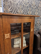 Harvey Ellis Wooden bookshelf with glass doors displaying books and decorative items on a white background