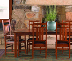 Harvey Ellis Dining table set with wooden chairs in front of a stone fireplace.