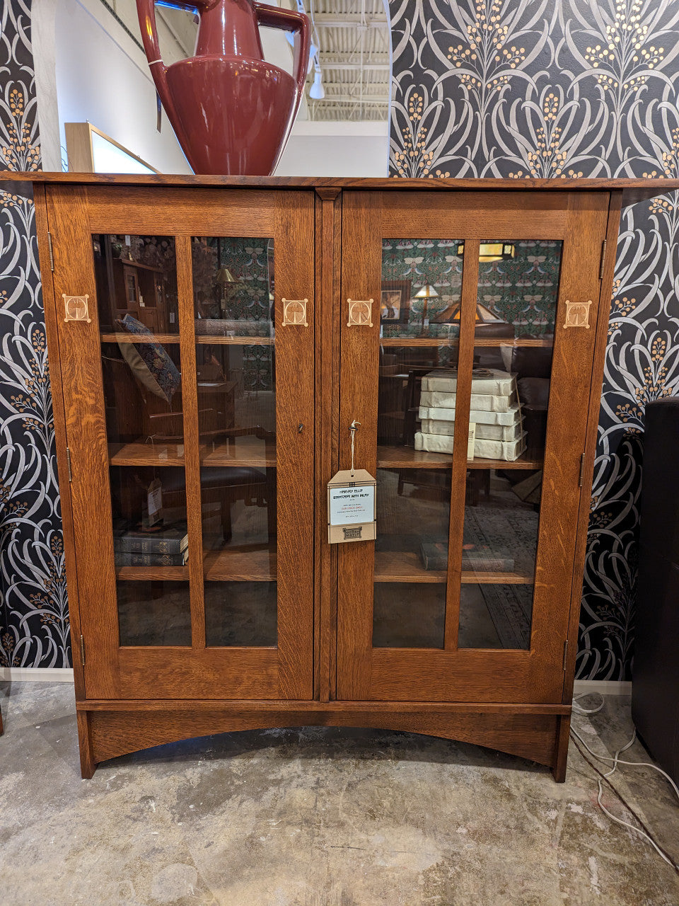 Harvey Ellis Wooden bookshelf with glass doors displaying books and decorative items on a white background