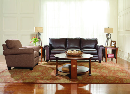 Living room with brown sofa, armchair, and coffee table on a patterned rug.