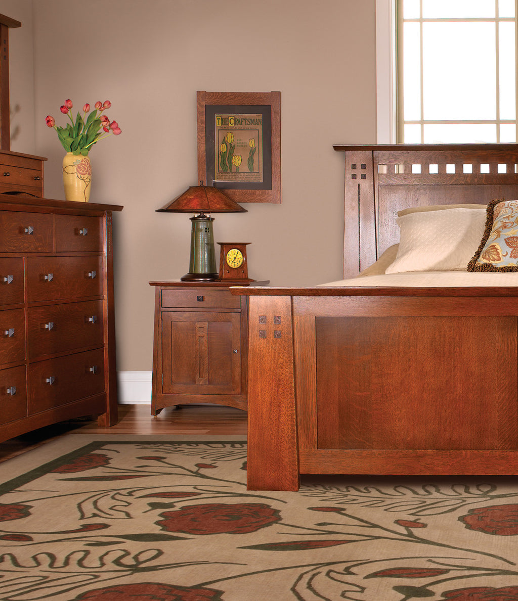Wooden bedroom furniture set with a lamp, clock, and decorative items on a patterned rug.