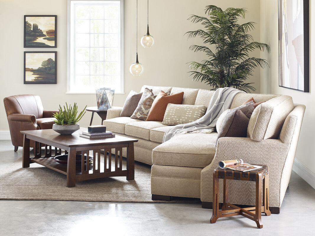 Living room with beige sectional sofa, wooden coffee table, and armchair. Stickley Highlands Cocktail table with a shelf. In cherry wood or oak. 