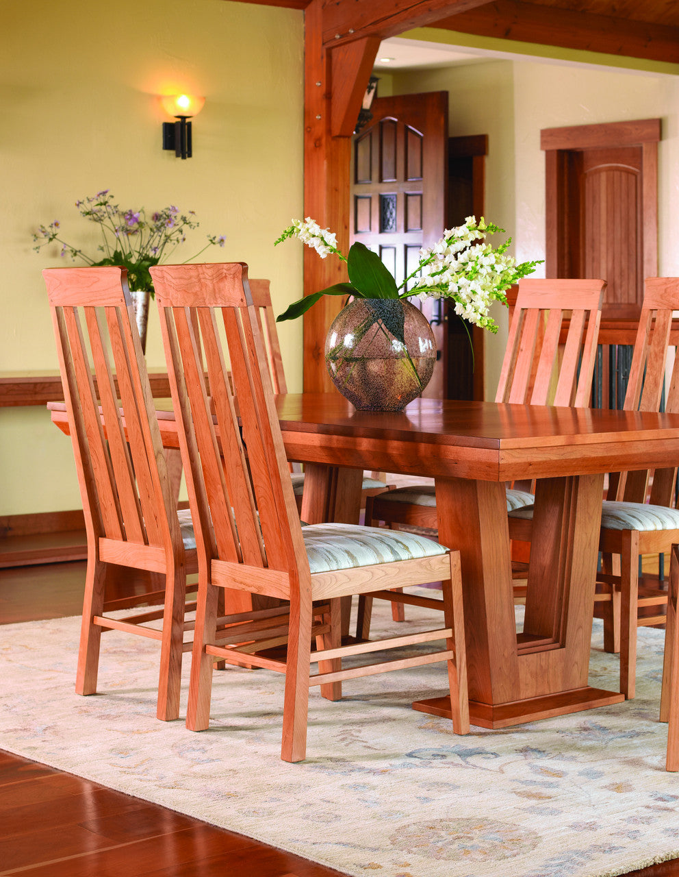 Wooden dining table with chairs in a room with a lamp and decorative elements.