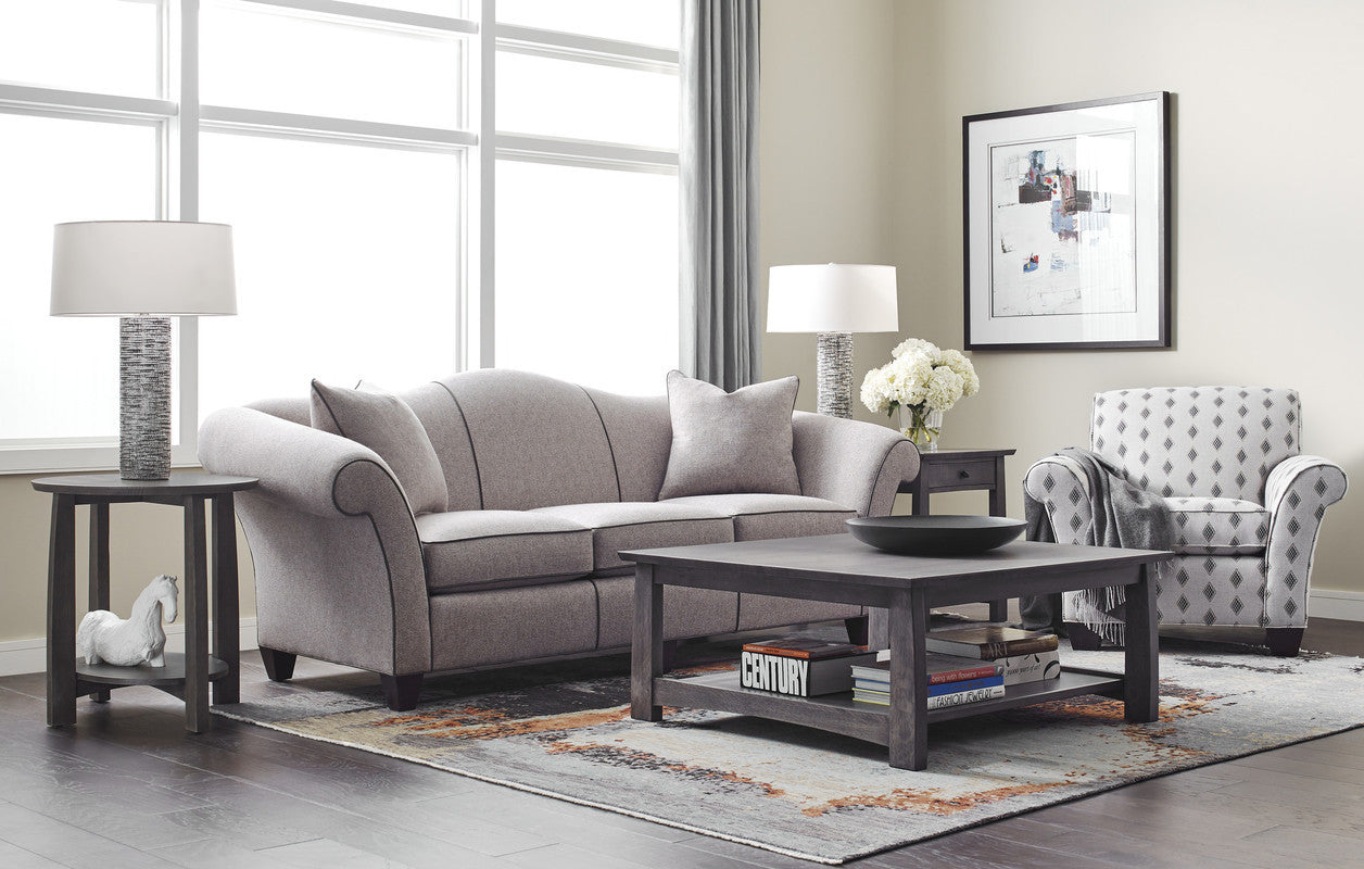 Living room with gray sofa, coffee table, and armchair near large windows.