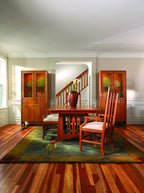 Dining room with wooden furniture, including a table and chairs, and a staircase in the background.