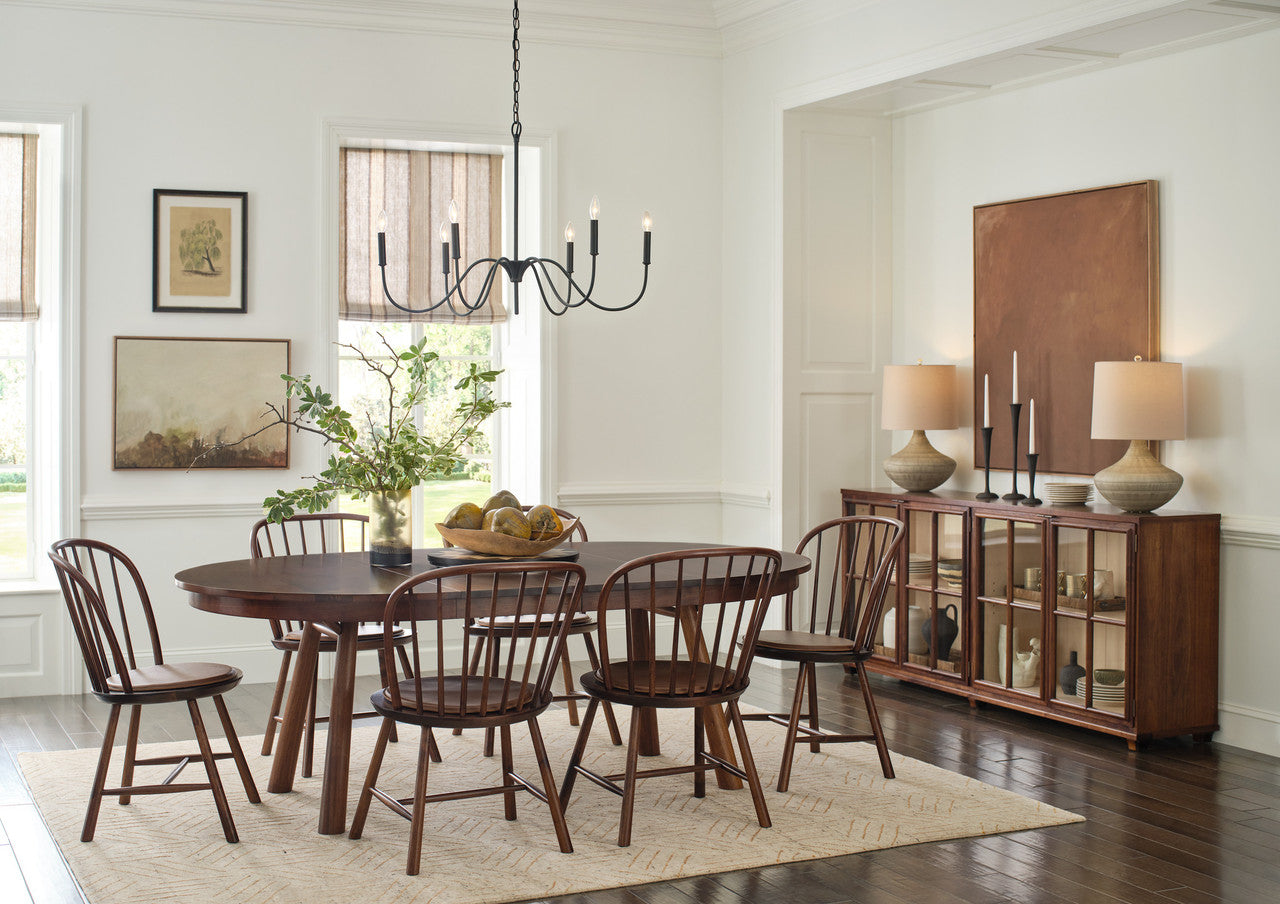 Dining room with wooden table and chairs, chandelier, and sideboard.