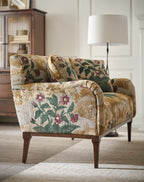 Floral-patterned sofa in a living room setting with a lamp and cabinet.