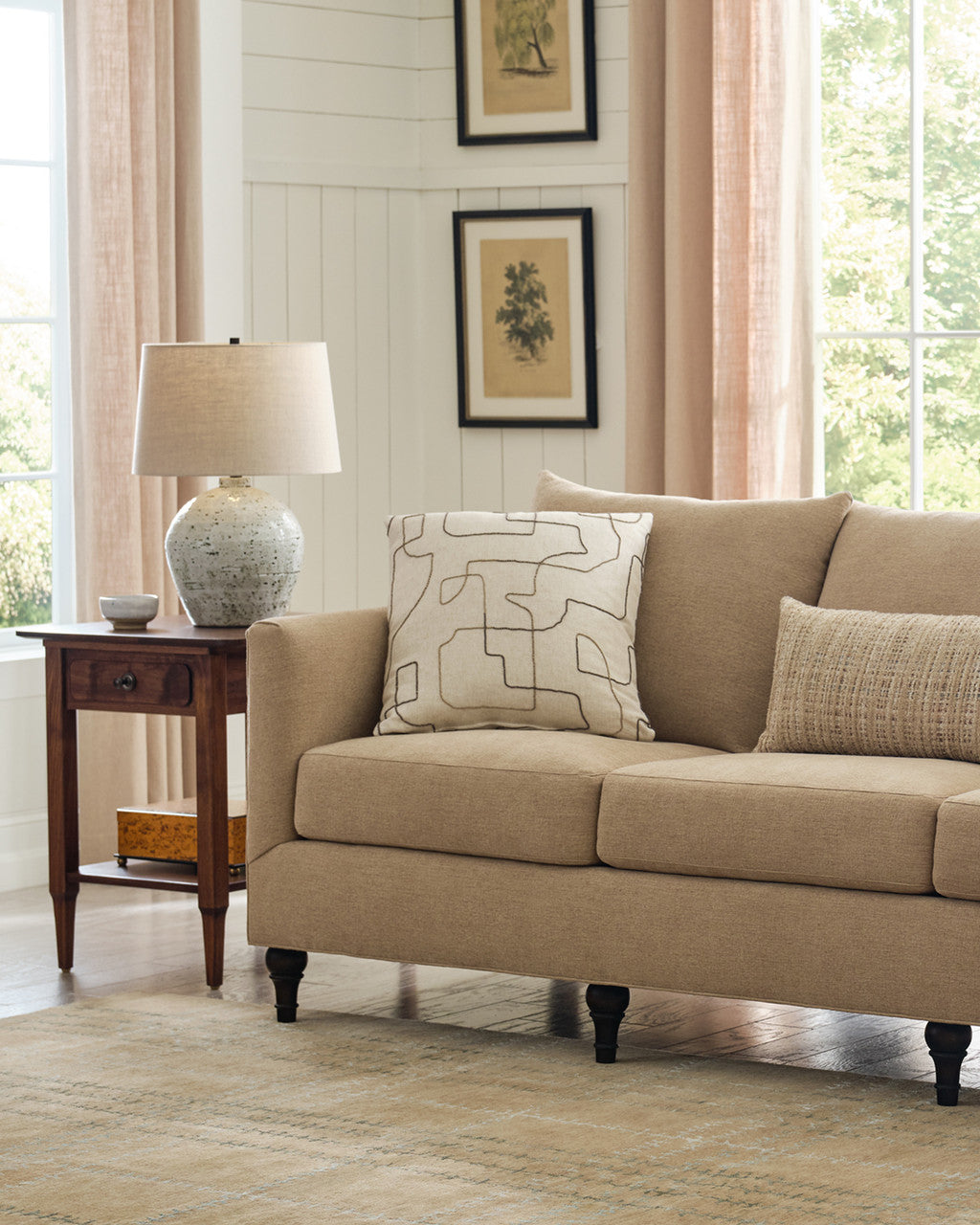 Beige sofa in a living room with a side table and decorative pillows.