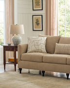 Beige sofa in a living room with a side table and decorative pillows.