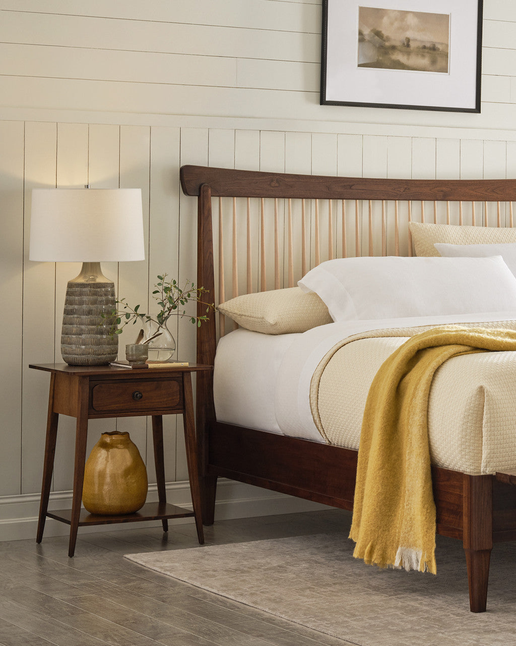 Wooden bed with white bedding and a yellow blanket in a bedroom setting.