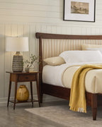 Wooden bed with white bedding and a yellow blanket in a bedroom setting.