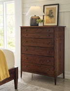 Wooden dresser with decorative items in a room with a bed and window.